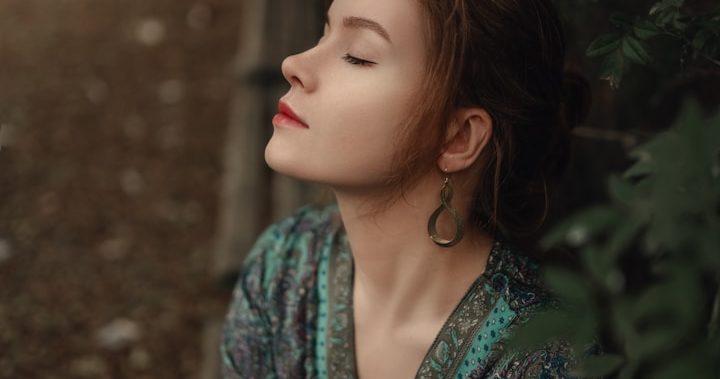 Frau mit geschlossenen Augen atmet ruhig in der Natur - Symbol für Entspannung, Regulation und innere Balance.